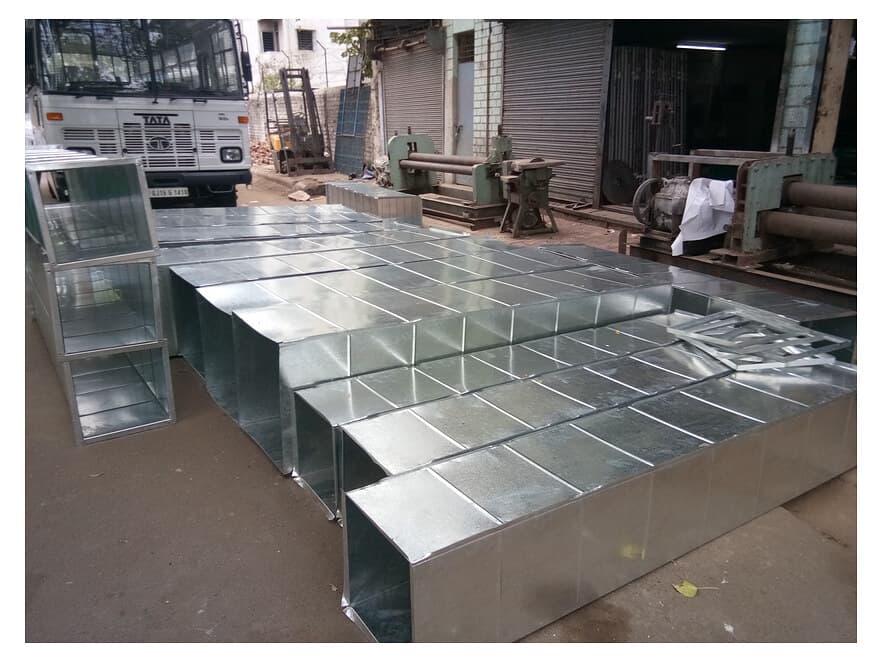 Galvanized rectangular duct sections stacked on the factory floor.